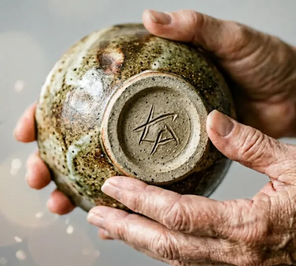 Close examination of artisan ceramic piece showing unique handcrafted surface texture and maker's mark