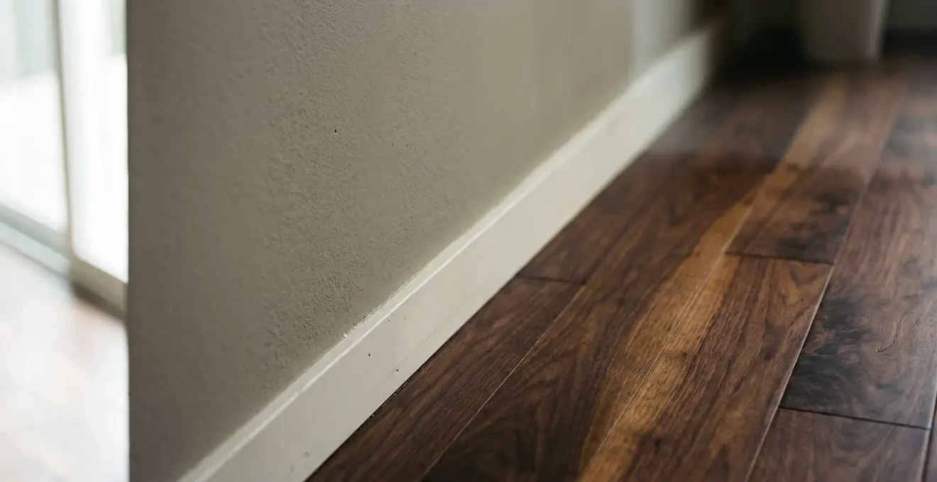 Close-up detail of matte painted wall meeting dark hardwood flooring showing color undertone interaction