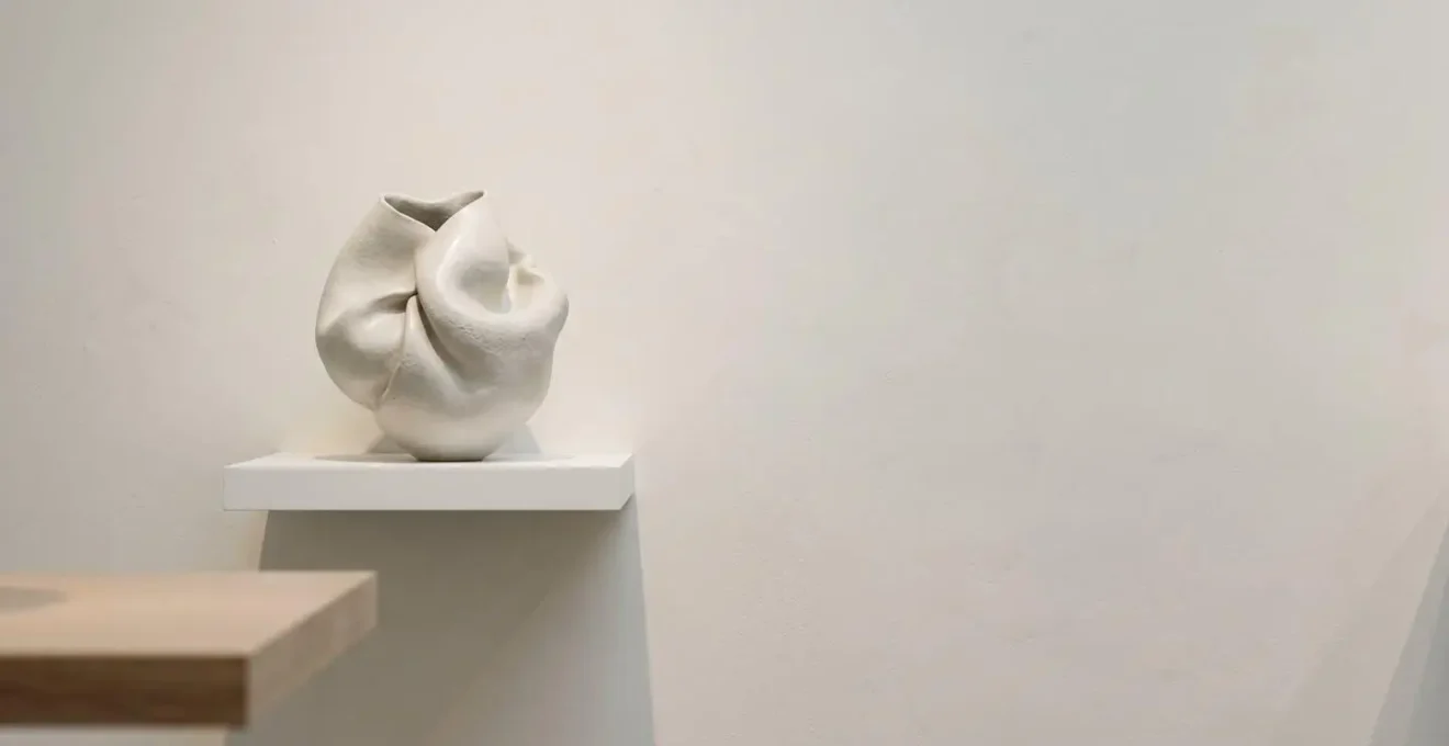 Professional gallery-style wall mount system securing a sculptural ceramic art piece with invisible hardware on a floating shelf.