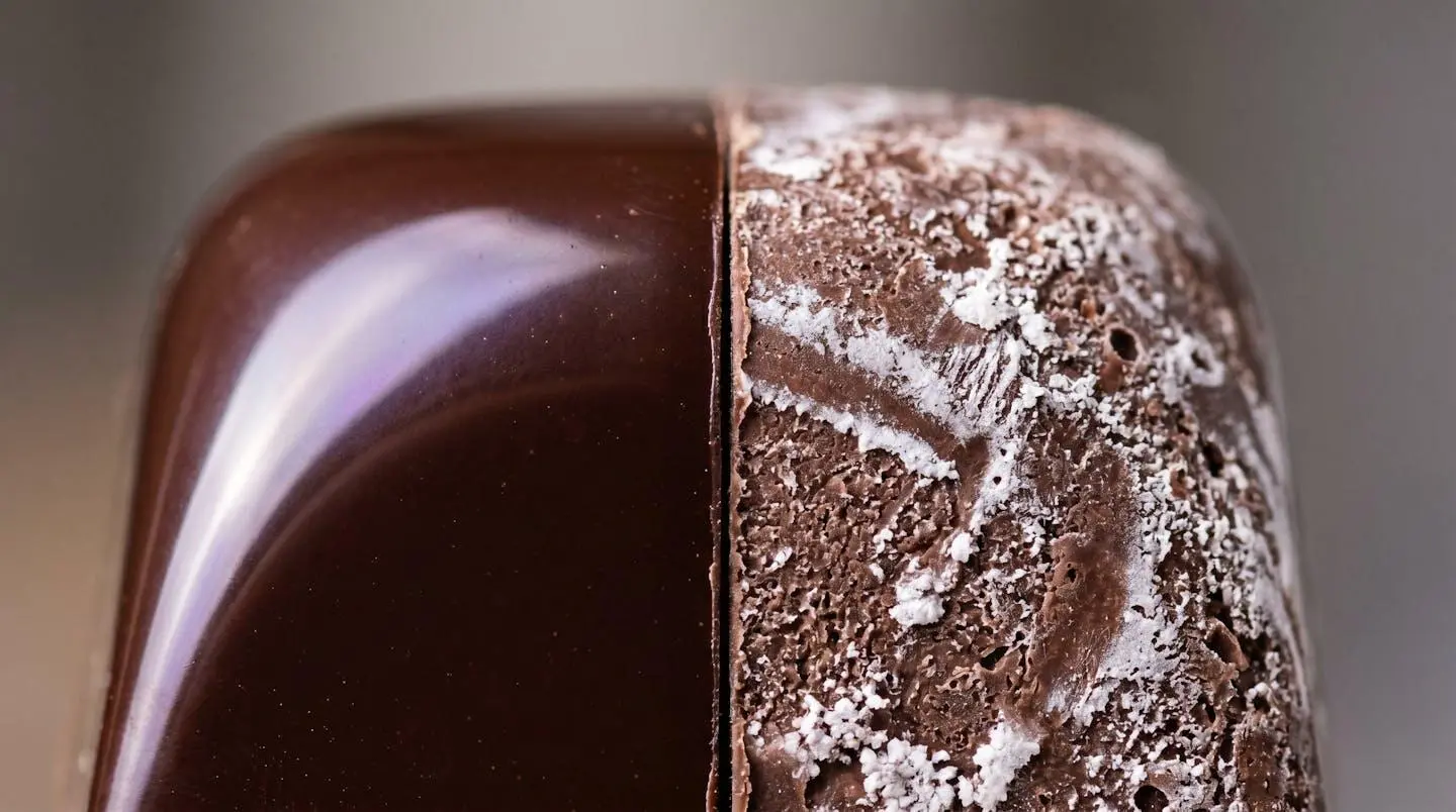 Close-up comparison of properly tempered glossy chocolate versus bloomed chocolate showing crystal formation differences